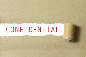 Red color confidential word written on torn paper white background